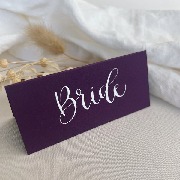 Purple place card with name written in white ink calligraphy