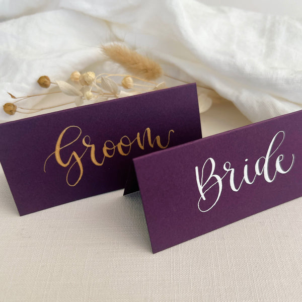 Purple place card with name written in gold ink calligraphy