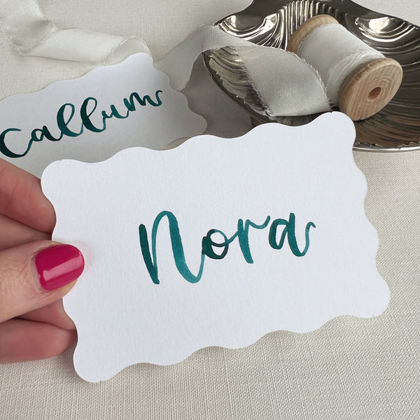 Wavy white place card with hand written name in teal ink