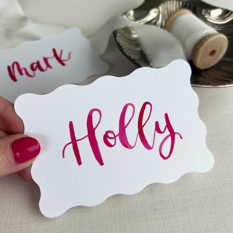 Wavy white place card with name written in pink ink